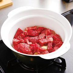 ふた付き鍋につぶしたにんにくを入れ、その上からオリーブオイルをかけて中火にかける。香りが出てきたら①を入れ、あまり混ぜないで肉の表面に焼き目が付くように焼く。