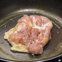 鶏肉の身の部分に塩（３つまみ）と黒こしょう（２つまみ）をふる。フライパンに油をひかずに皮の部分を下にして入れて中火にかけ、皮にしっかりと焼き色がつくまで返さないで焼く。【ポイント１】【ポイント２】