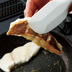 フライパンにオリーブオイル（大さじ１）を入れ加熱し、（１）の真鯛を皮目から入れる。中火で加熱し皮目がある程度焼けたらにんにくを入れる。裏返さず、皮目だけに焼き色をしっかり付ける。