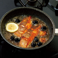 真鯛を返したらアンチョビを入れてくずすように焼き、ケッパー、白ワイン、水を入れて強めの中火にする。レモン、ブラックオリーブを加えて蓋をし２～３分蒸し焼きにする。ミニトマトを加えてサッと加熱し、塩少々を加える。