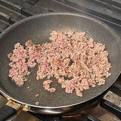 別のフライパンに合いびき肉を入れ、ひき肉を押し付けながら強火で炒める。香ばしく色づいたら（１）の鍋に移す。肉汁が残ったフライパンに赤ワインを入れ、強火で煮詰める。半量程度になったら（１）の鍋に入れ、水、トマトペースト、フォン・ド・ヴォーを加え、弱火で１０分程度煮込む。